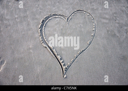 A forma di cuore scolpiti nella sabbia in spiaggia Foto Stock