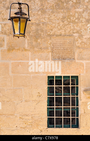 Esterno con finestra decorata e lampada da parete in Mdina, Malta. Foto Stock