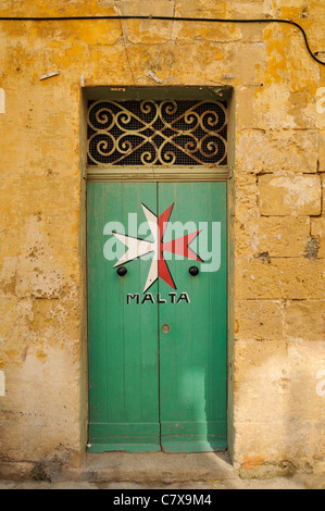 Croce di Malta dipinta su una vecchia porta verde, Malta. Foto Stock