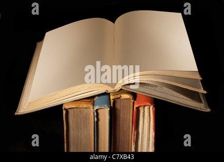 Libro aperto con le pagine in bianco sulla parte superiore del vecchio usurato spine su nero Foto Stock