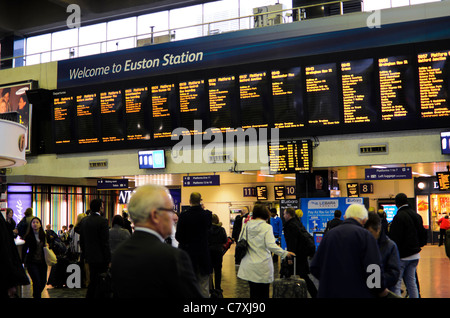 Passeggeri controllare gli orari di partenza nel piazzale della stazione di Euston, London, England. Foto Stock
