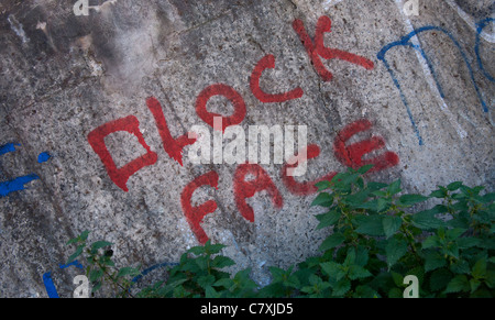 Graffiti a fronte di clock Scrawl e Graffiti su un muro in St Helens, Merseyside, Regno Unito Foto Stock