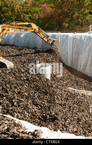 Realizzazione di un bacino di ritenzione di acqua di pioggia. Riempito con un grind di pneumatici usati. Coperta con una lastra di calcestruzzo che servirà come parcheggio. Foto Stock