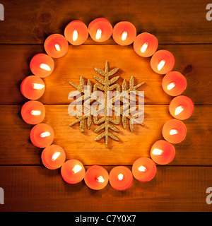 Natale candele cerchio nel corso del legno dorato e il simbolo del fiocco di neve Foto Stock