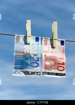 Concetto che rappresenta il riciclaggio di denaro Euro 20 e Euro banconote da 10 ancorato su una linea di lavaggio Foto Stock