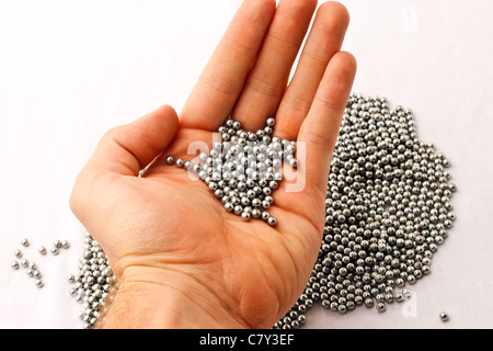 BB di pellet in mano sul palo di argento agglomerati in forma di pellets Foto Stock