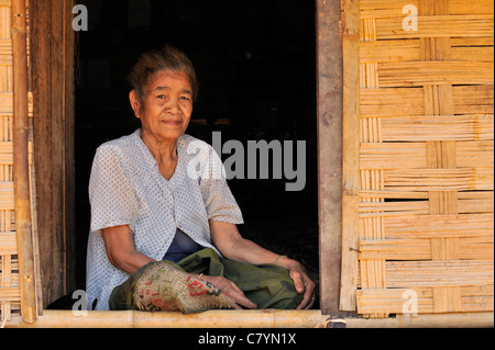 Khmu hill tribe, vecchia donna seduta nella porta della sua casa, Luang Prabang, Laos Foto Stock