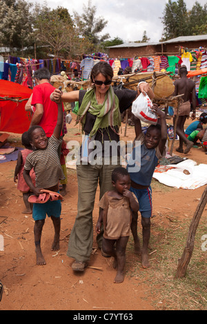 Bambini etiopi appeso su una donna occidentale le mani in un mercato, Keyafa, Valle dell'Omo, Etiopia, Africa Foto Stock