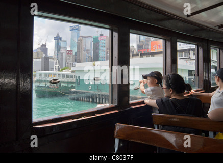 Un bambino guarda attraverso la finestra di una Star Ferry centrale di avvicinamento a Hong Kong Foto Stock