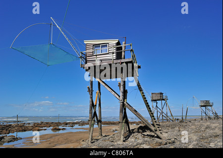 Carrelet tradizionali capanne di pesca con reti di sollevamento sulla spiaggia con la bassa marea, Saint-Michel-Chef-Chef, Loire-Atlantique, Francia Foto Stock