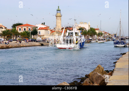 Barca da pesca ritorna in porto Le Grau-du-Roi circondata da gabbiani Foto Stock