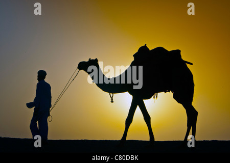 Silhouette di uomo e cammello sunrise deserto di Thar vicino Khuri Rajasthan in India Foto Stock