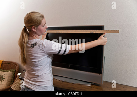Ragazza adolescente misure le dimensioni di una TV 32 pollici schermo. Signor © Myrleen Pearson Foto Stock