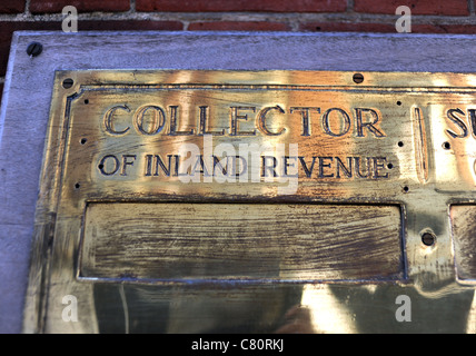 Collettore di Inland Revenue le tasse nel Regno Unito su un segno di ottone piastra contro una parete Foto Stock