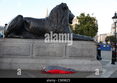Senzatetto traversina sotto uno dei Lions a Trafalgar Square, Londra Foto Stock