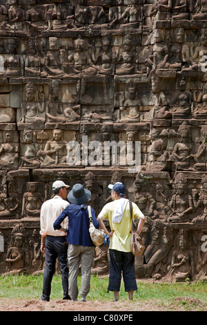 Tourist contemplando i rilievi sul lebbroso re terrazza. Angkor Thom. I templi di Angkor. Cambogia Foto Stock
