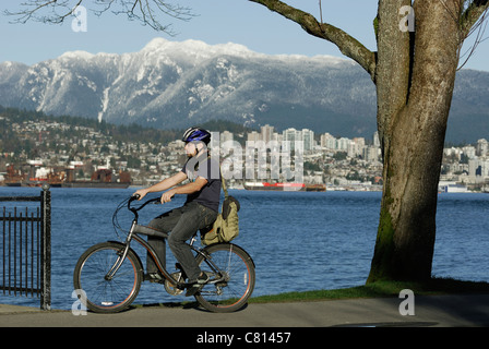 Giovane uomo in bicicletta lungo il Parco Stanley seawall su una giornata invernale nella Città di Vancouver. Foto Stock