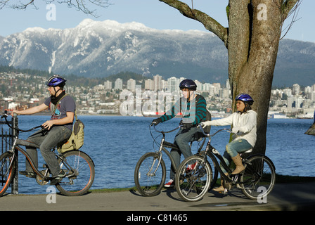 I giovani adulti di andare in bicicletta lungo il Parco Stanley seawall su una giornata invernale nella Città di Vancouver. Foto Stock