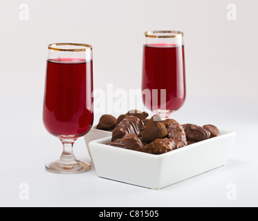 Acquavite di ciliegie e cioccolatini su un tavolo bianco. Foto Stock