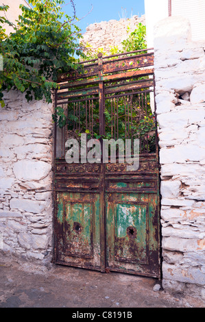 Vecchia porta arrugginito con peeling paint che conduce ad un cortile abbandonato sul Greco Cyclade isola di Amorgos. Foto Stock