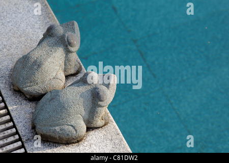 Paesaggio di pietra scolpita rane ornamentali rivolta verso Nord Est a bordo piscina piscina con acqua blu spazio raccolto spazio copia e in posizione orizzontale Foto Stock