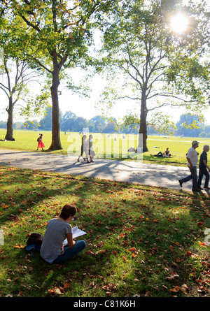 Una donna è seduta sul prato della lettura in Hyde Park, Londra su una calda sera alla fine di settembre 2011 Foto Stock