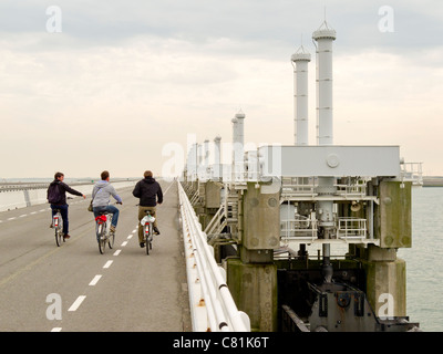 I ciclisti su Oosterscheldekering, la Schelda orientale. storm. I picchi di barriera, parte del progetto Delta, Zeeland, Paesi Bassi Foto Stock