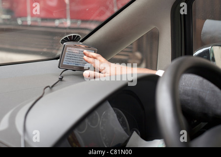 Driver maschio impostazione di un tomtom satnav in suo automobile Foto Stock
