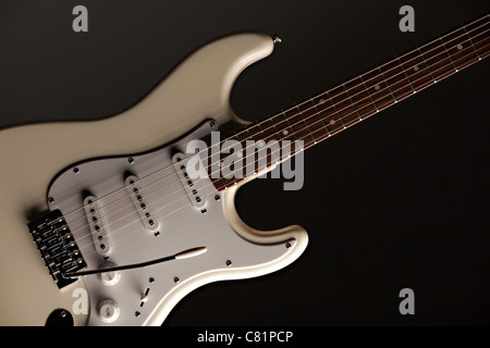 Un bianco di chitarra elettrica isolata contro uno sfondo nero con copia spazio. Foto Stock