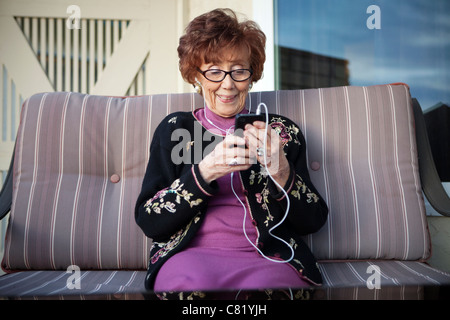 Senior donna caucasica ascoltando mp3 player Foto Stock