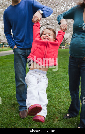 I genitori caucasici figlia oscillante all'aperto Foto Stock