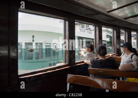 Un bambino guarda attraverso la finestra di una Star Ferry centrale di avvicinamento a Hong Kong Foto Stock