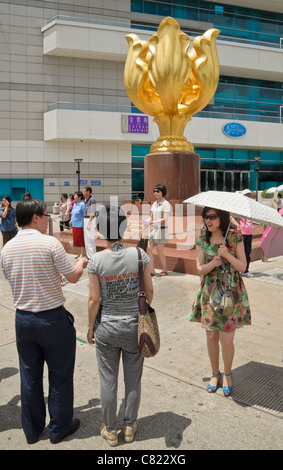 I turisti posano per le foto in Piazza Golden Bauhinia accanto al Centro Convegni ed Esposizioni di Hong Kong a Wan Chai Foto Stock