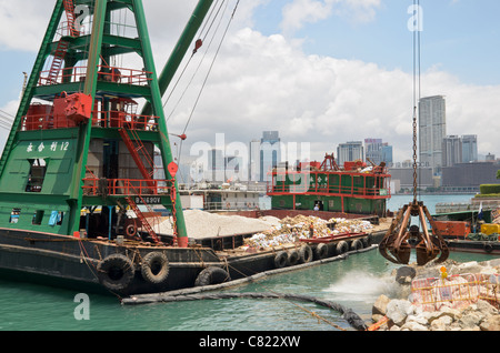 Chiatta dragaggio con gru di sollevamento rocce nella bonifica di terreni lungo la Wan Chai waterfront, Hong Kong Foto Stock