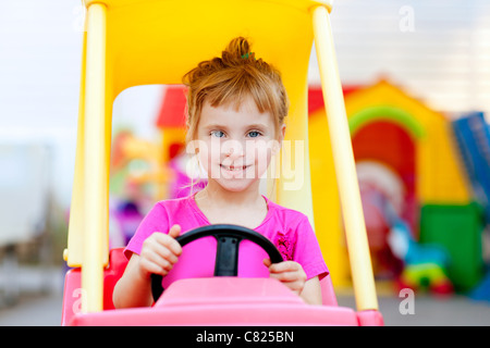 Blonde Bambini ragazza guida auto giocattolo giallo Foto Stock