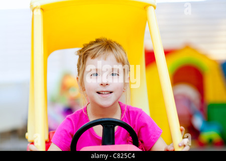 Blonde Bambini ragazza guida auto giocattolo giallo Foto Stock