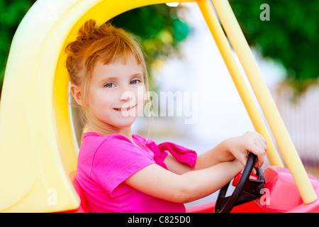 Blonde Bambini ragazza guida auto giocattolo giallo Foto Stock