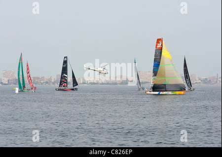 Da sinistra a destra: squadre di Groupama Camper, Puma, Telefonica, Sanya e Abu Dhabi sono seguiti da un elicottero di media durante una regata di prova prima della Volvo Ocean Race nella baia di Alicante, Spagna Foto Stock