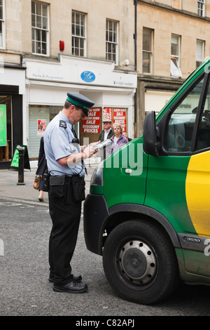 Vigile o esecuzione civile funzionario che rilascia un reato di parcheggio ticket a un furgone parcheggiato illegalmente in strada. Inghilterra Regno Unito Gran Bretagna Foto Stock