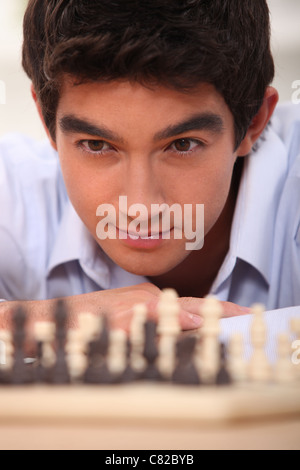 Giovani chessplayer cercando focalizzata Foto Stock