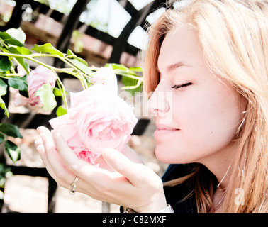 Piuttosto giovane donna odorare una rosa Foto Stock