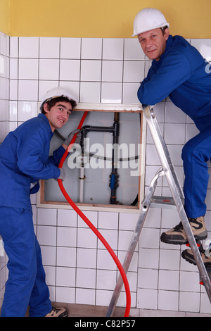 Gli idraulici a lavorare in una stanza piastrellata Foto Stock