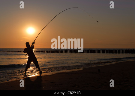 Il pescatore al tramonto sulla spiaggia di Westenschouwen, Zeeland, Paesi Bassi Foto Stock