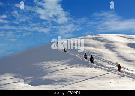 Gli appassionati di snowboard a piedi su per la montagna Foto Stock