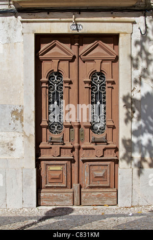 Weathered marrone porta in legno con maniglie in ottone nella città medievale di Estremoz Foto Stock