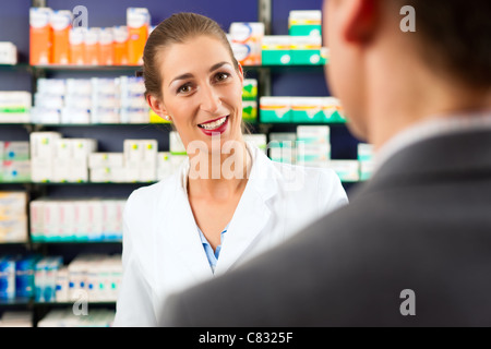 Il farmacista femmina di avvalersi della consulenza di un cliente in farmacia Foto Stock