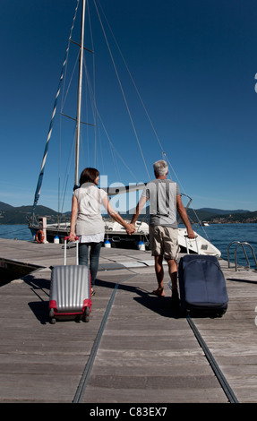 Anziana coppia di rotolamento sui bagagli pier Foto Stock