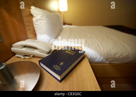 La Santa Bibbia poste dall'gideons sul tavolo accanto all'interno di un hotel a 4 stelle la camera da letto Foto Stock