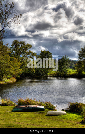 Calma e tranquilla in scena il Trossachs, Scozia, piccolo loch, lago, con due capovolta barche a remi a bordo di acqua Foto Stock