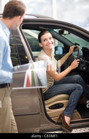 Donna ammirando auto in showroom Foto Stock